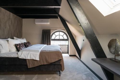 a attic bedroom with a bed and a window at Stadslogement De Vooruitgang in Sneek