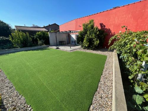 a garden with green grass next to a red wall at LMB Alojamento local in Penacova