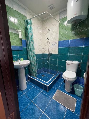 a blue tiled bathroom with a toilet and a sink at Guest House Yukon in Bosteri
