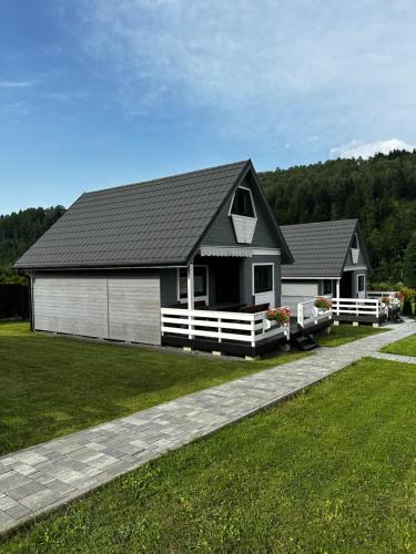 a house with a black roof and a grass yard at Siedlisko Leśnica - domki całoroczne Brenna in Brenna