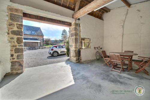 a patio with a table and a car parked in a garage at La clef des champs in Kérien