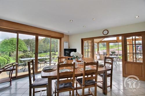 une salle à manger avec une table, des chaises et des fenêtres dans l'établissement La vallee de leber, à Plouasne