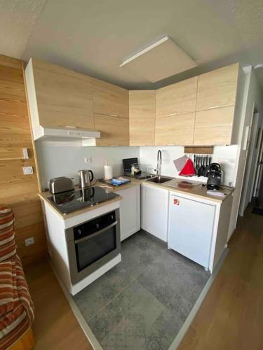 - une petite cuisine avec des appareils blancs et des armoires en bois dans l'établissement Studio rénové, pied des pistes, à Allevard