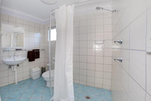 a bathroom with a shower and a toilet and a sink at Bali Hi Motel in Tuncurry