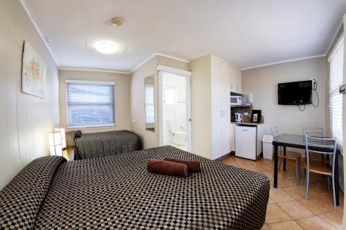 a bedroom with a bed and a table and a kitchen at Bali Hi Motel in Tuncurry