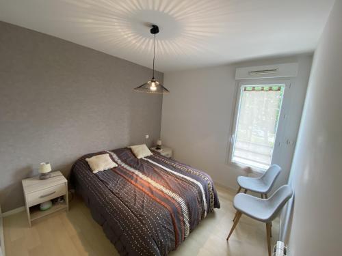 une chambre avec un lit, une chaise et une fenêtre dans l'établissement Appartement Calme Puits d Enfer Parking, à Château-dʼOlonne