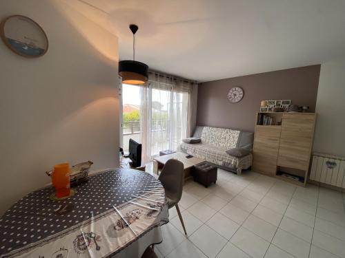 un salon avec une table et un canapé dans l'établissement Appartement Calme Puits d Enfer Parking, à Château-dʼOlonne