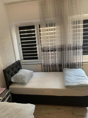 a bed in a room with two windows at Unterkunft Mara in Oberhausen