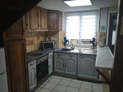 une cuisine avec des armoires blanches, un évier et une fenêtre dans l'établissement Petite maison de village, à Chamouilley