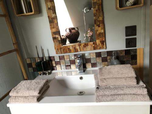 La salle de bains est pourvue d'un lavabo blanc et de serviettes. dans l'établissement La Thibautière, à Blaison-Gohier