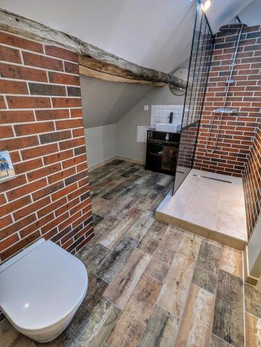 La salle de bains est pourvue de toilettes et d'un mur en briques. dans l'établissement LE CLOS DES LYS - Chambres avec jacuzzi - Nemours, à Treuzy-Levelay