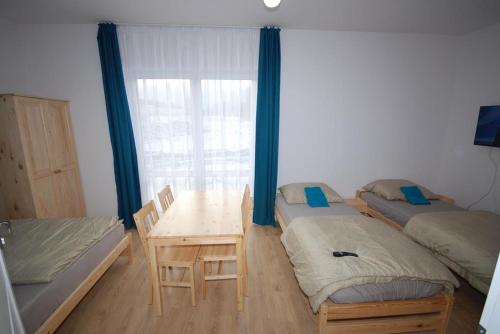 a room with two beds and a table and a window at Pęglity jezioro in Gietrzwałd