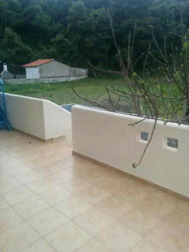 a white retaining wall in a yard with a tree at Angel in Káto Alepokhórion