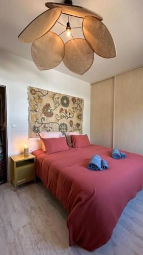 - une chambre avec un grand lit rouge et un lustre dans l'établissement LA Maison du Pressoir, à Les Noyers