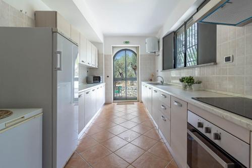 a large kitchen with white cabinets and a large window at Il Castello degli Ulivi-Agriturismo in natura in Roccella Ionica