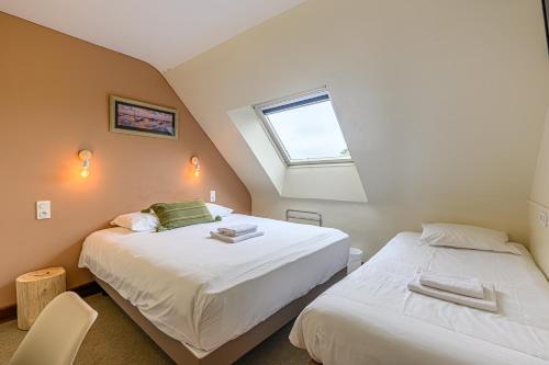 two beds in a room with a window at Naéco Erdeven in Erdeven