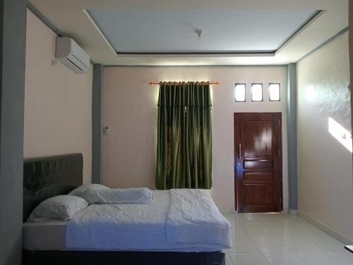 a bedroom with a bed and a green curtain at Yusilver Guest House in Labuan Bajo