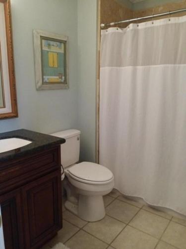 Un baño con inodoro y cortina de ducha. en Boardwalk#3, en Pensacola