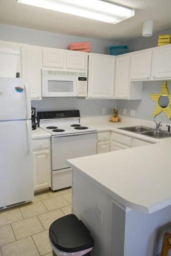 a kitchen with white cabinets and white appliances at Grand Caribbean 214W in Pensacola