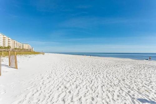 a white sandy beach with a building and the ocean at Grand Caribbean 214W in Pensacola