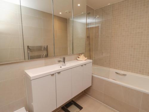 a bathroom with a sink and a mirror and a tub at Monowai Heights in St Ives