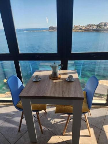 a table and chairs with a table and a view of the water at Seafront 2 bedroom apartment in Marsaskala