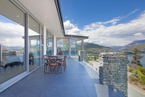 a house with a balcony with a table and chairs at Lake Views at Aspen House by Amazing Accom in Queenstown