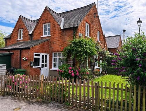 a red brick house with a wooden fence at Grade II listed Victorian cottage in Windsor