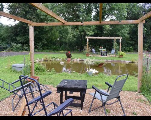 a group of chairs and a table in front of a pond at Squirrels-oaks in Yalding