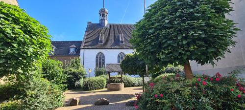 a large white building with a tree in a garden at Ferienwohnung "Erika" Rees am Niederrhein in Rees