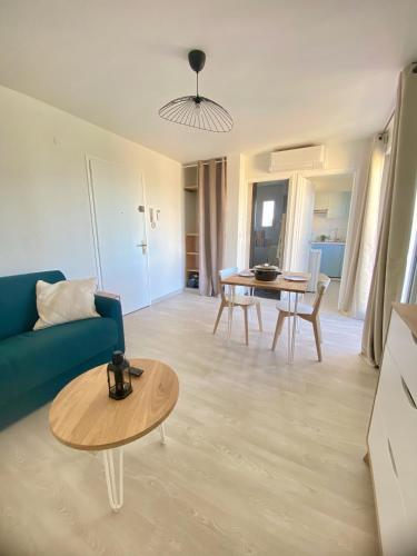 un salon avec un canapé bleu et une table dans l'établissement Le Belvédère - Studio avec vue YourHostHelper, à Montpellier