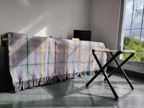 a blanket is draped over a table with a chair at Liv House in Kandy