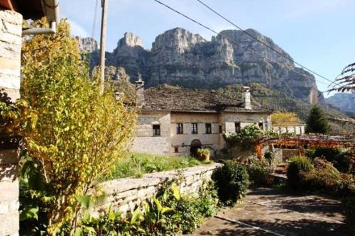 an old building with a mountain in the background at Astraka Guesthouse I in Papigko
