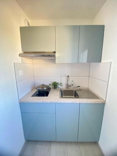 une cuisine avec des armoires blanches et un évier dans l'établissement Le Belvédère - Studio avec vue YourHostHelper, à Montpellier