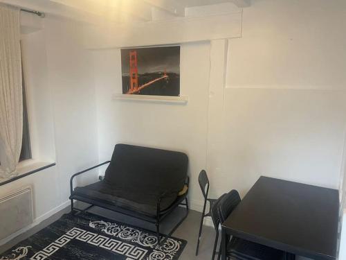 a room with a chair and a table and a picture at Belle petite maison in Montfermeil