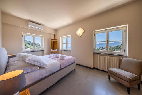 Un dormitorio con una cama y una silla y ventanas. en VILLA DUFOUR 1 Lusso, Spazio e Vista Mare, en Zoagli