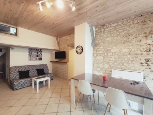- un salon avec un mur en pierre, une table et des chaises dans l'établissement Maison Atypique 76m² - Centre La Roche-Posay, Terrasse, Jardin Clôturé - FR-1-541-60, à La Roche-Posay
