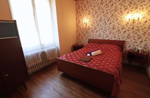 a bedroom with a bed with a red comforter at Maison Bienvenue chez Mémé in Treigny