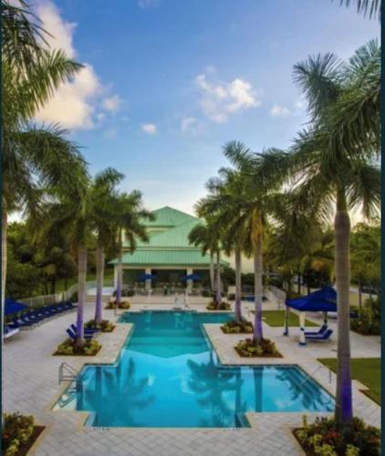 a pool with palm trees in front of a building at Doral 2-Story Villa 3 Bed 4 Bath at Provident Doral at The Blue Miami in Miami