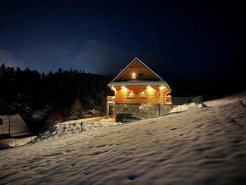 a cabin lit up with lights in the snow at night at Chata Trzy Wierchy in Wisła