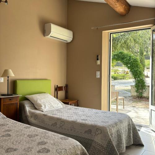 a bedroom with two beds and a sliding glass door at Domaine Saint Julien in Buis-les-Baronnies