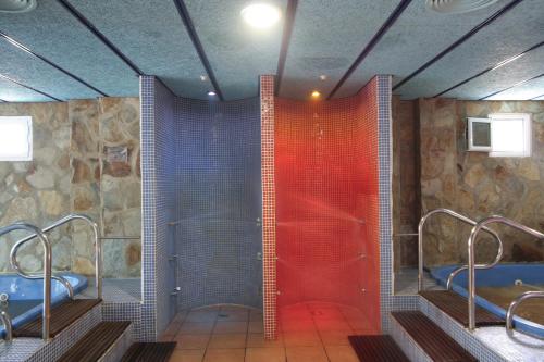 baño con 2 lavabos y ducha de cristal rojo en Hotel Balneario Fuentes del Trampal, en Carmonita