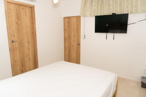 Un dormitorio con una cama y un televisor en la pared. en Hostal Las Guaduas, en Santa Marta