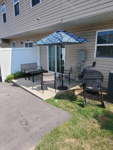 a patio with a grill and chairs and an umbrella at Cozy Nest: Where Love Blossoms in Nashville