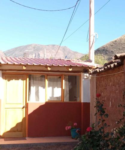 a house with a door and a mountain in the background at Wayqi Wasi in Pisac