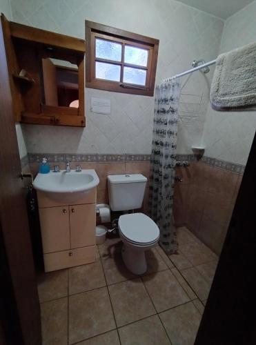 a bathroom with a toilet and a sink and a window at Casa de Silvina in El Bolsón