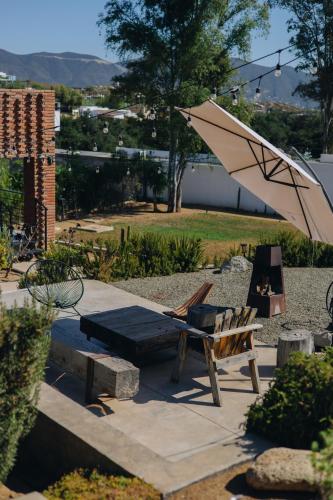 a patio with a chair and an umbrella and a bench at Hotel Otero Valle de Guadalupe in Valle de Guadalupe