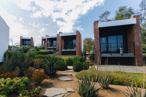 a row of houses in a garden with plants at Hotel Otero Valle de Guadalupe in Valle de Guadalupe