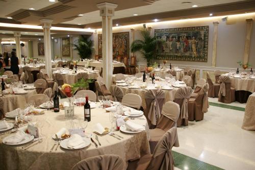 un salón de banquetes lleno de mesas y sillas con ropa de cama blanca en Hotel Plaza Manjón, en Villanueva del Arzobispo