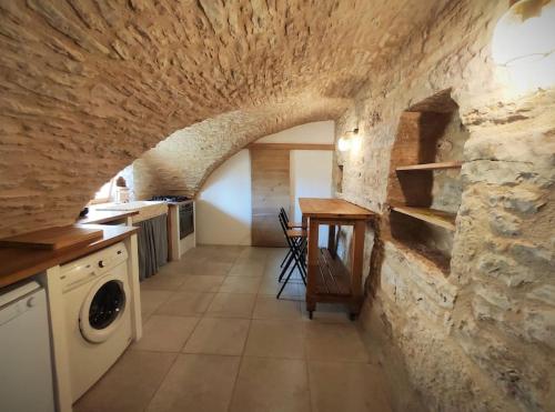 - une cuisine avec un mur en pierre, un lave-linge et un sèche-linge dans l'établissement Grande grange atypique proche des Gorges du Tarn, à Saint-Georges-de-Lévéjac
